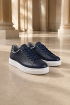 Navy pebbled leather low-top lace up sneakers with white rubber soles and textured navy pebbled leather finish