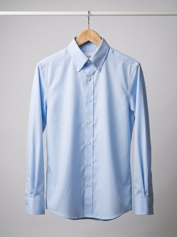 Light blue non-iron cotton dress shirt hanging wrinkle-free on a wooden hanger