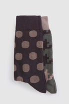 A pair of socks, one featuring a dark brown base with tan polka dots and the other displaying a pixelated camouflage pattern in shades of green and beige.