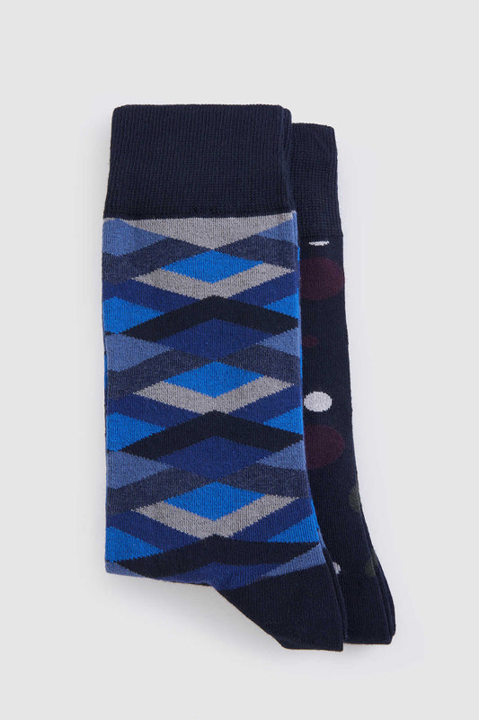 A pair of navy blue socks featuring a geometric argyle pattern in shades of blue and gray, with one sock displaying polka dots.