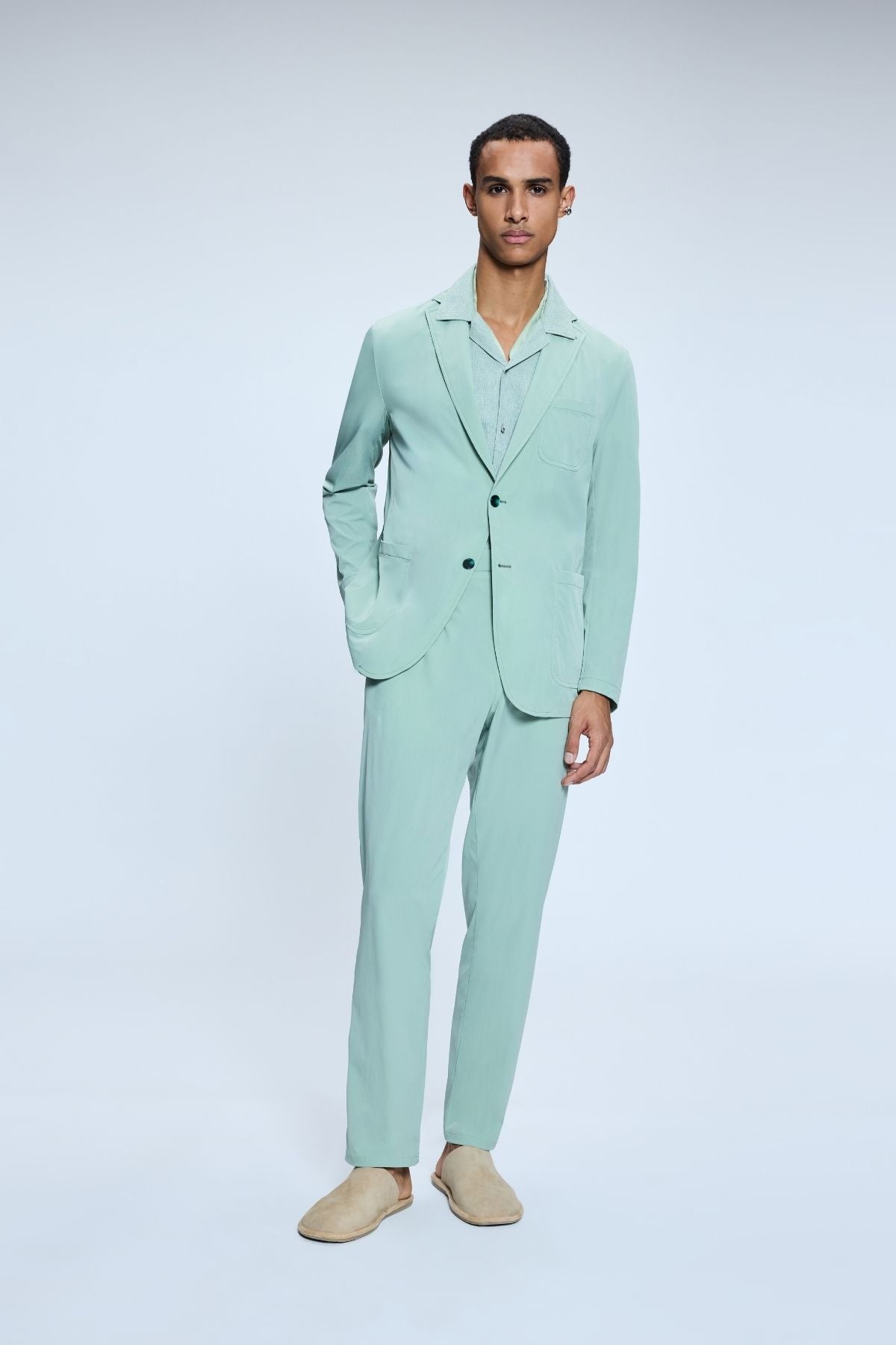 Model in sage green suit with matching shirt demonstrating bold color trend for 2025