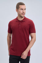 A man wearing a regular fit cotton burgundy polo t-shirt with short sleeves and a buttoned placket