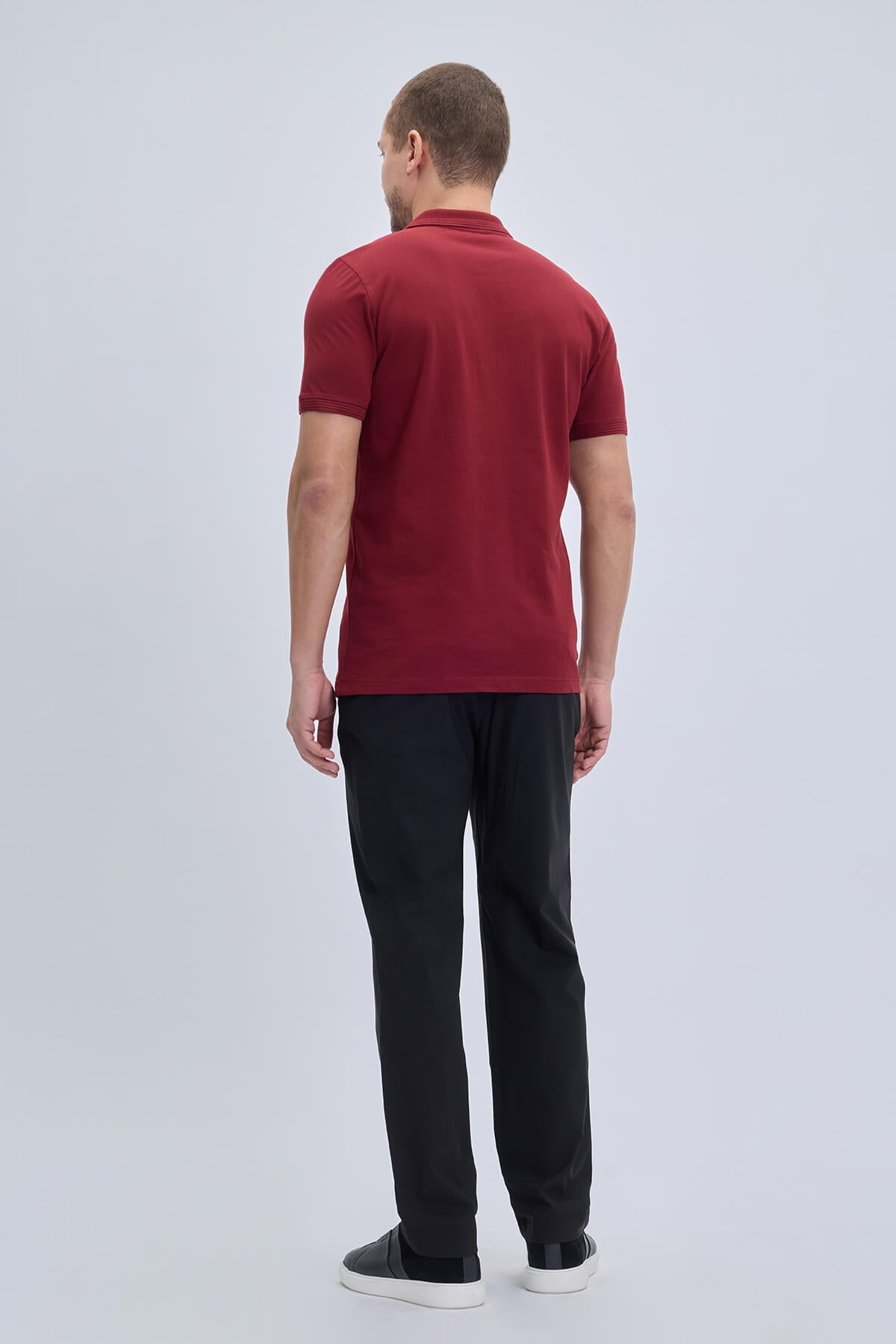 A man wearing a regular fit cotton burgundy polo t-shirt with ribbed collar and cuffs in solid red