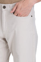 Beige denim trousers with a subtle textured weave and dark metal button accents.