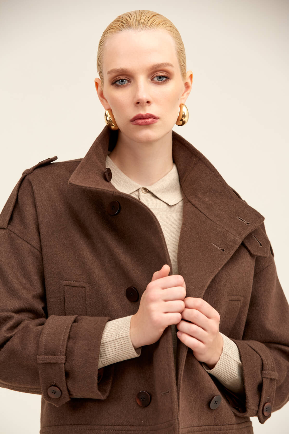 Brown woolen trench coat with a structured collar and double-breasted front.