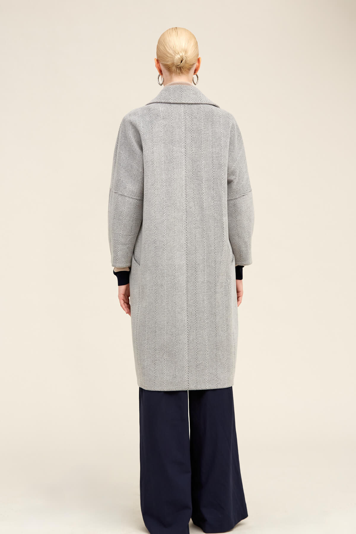 A light gray herringbone wool coat with a classic collar and black ribbed cuffs.