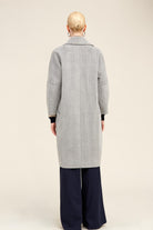 A light gray herringbone wool coat with a classic collar and black ribbed cuffs.