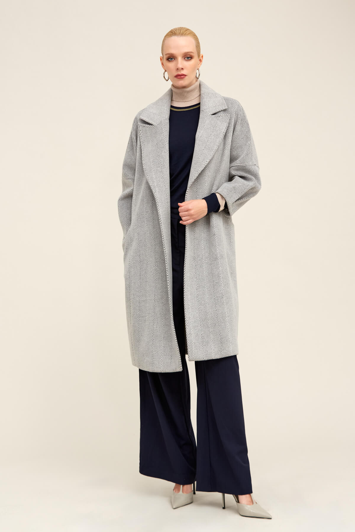 A light gray, longline coat with a subtle herringbone weave and wide lapels.