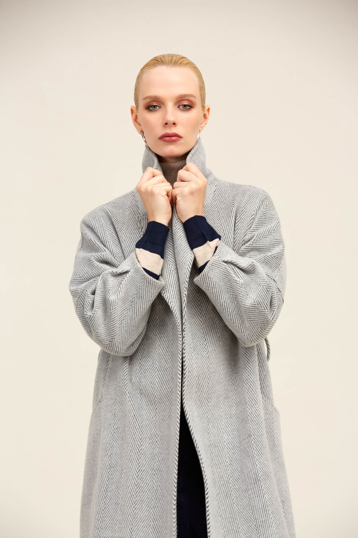 A light gray herringbone wool coat with navy and cream contrast cuffs.
