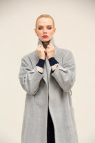 A light gray herringbone wool coat with navy and cream contrast cuffs.