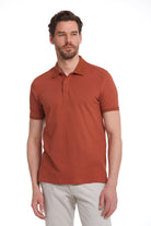 A man wearing a rust-colored, short-sleeved polo shirt with a classic collar and buttoned placket.