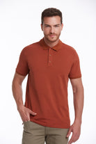 A man wearing a rust-colored, short-sleeved polo shirt with a ribbed collar and matching button placket.
