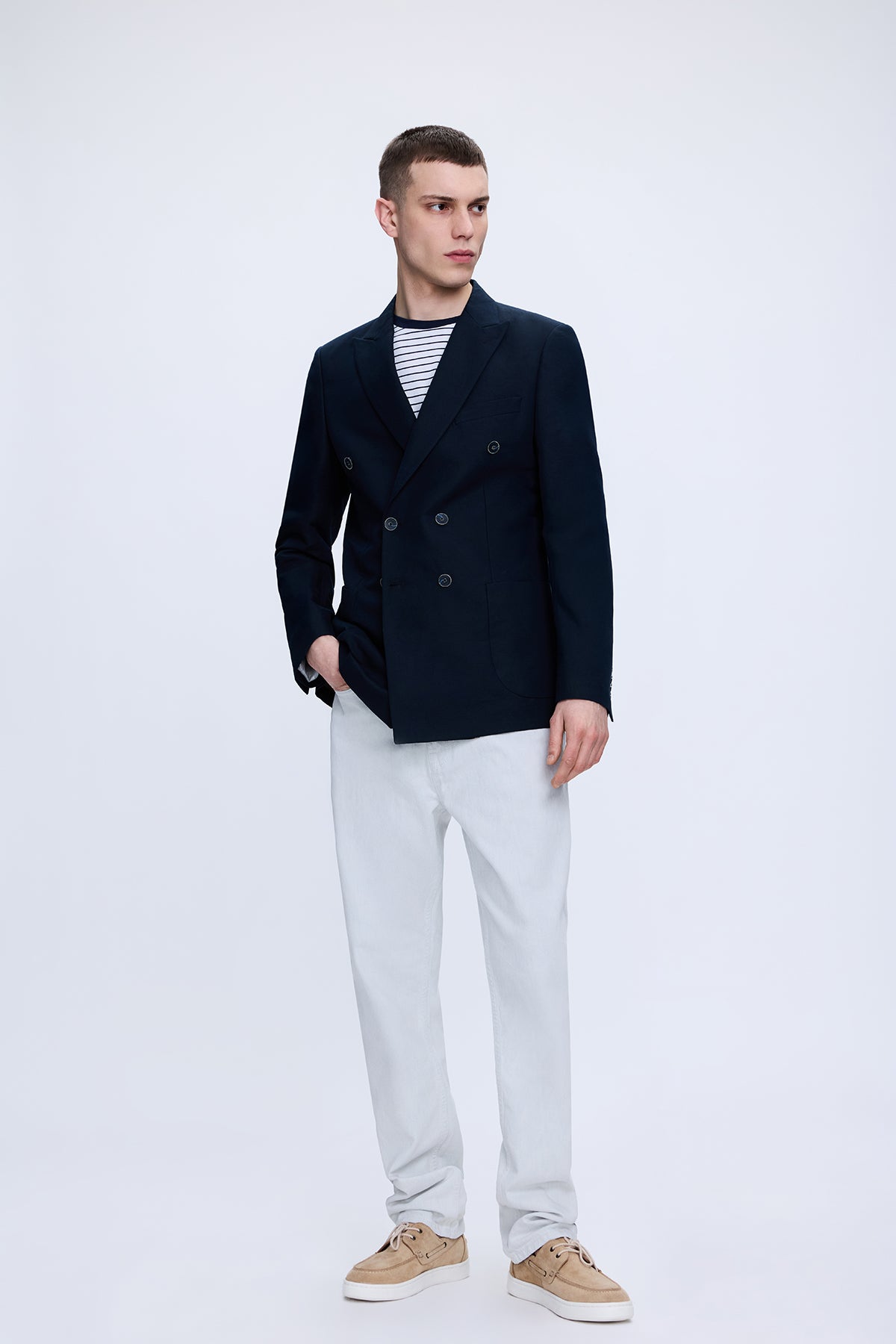 Navy blue double-breasted blazer paired with regular fit white cotton denim pants for a stylish casual look