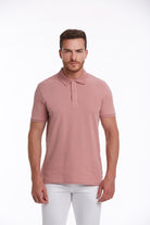 A man wearing a soft pink polo shirt with a classic collar and short sleeves.