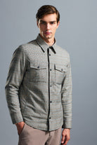 A men’s long-sleeved button-up shirt in a gray and black checkered pattern with two chest pockets, featuring dark buttons along the front placket.
