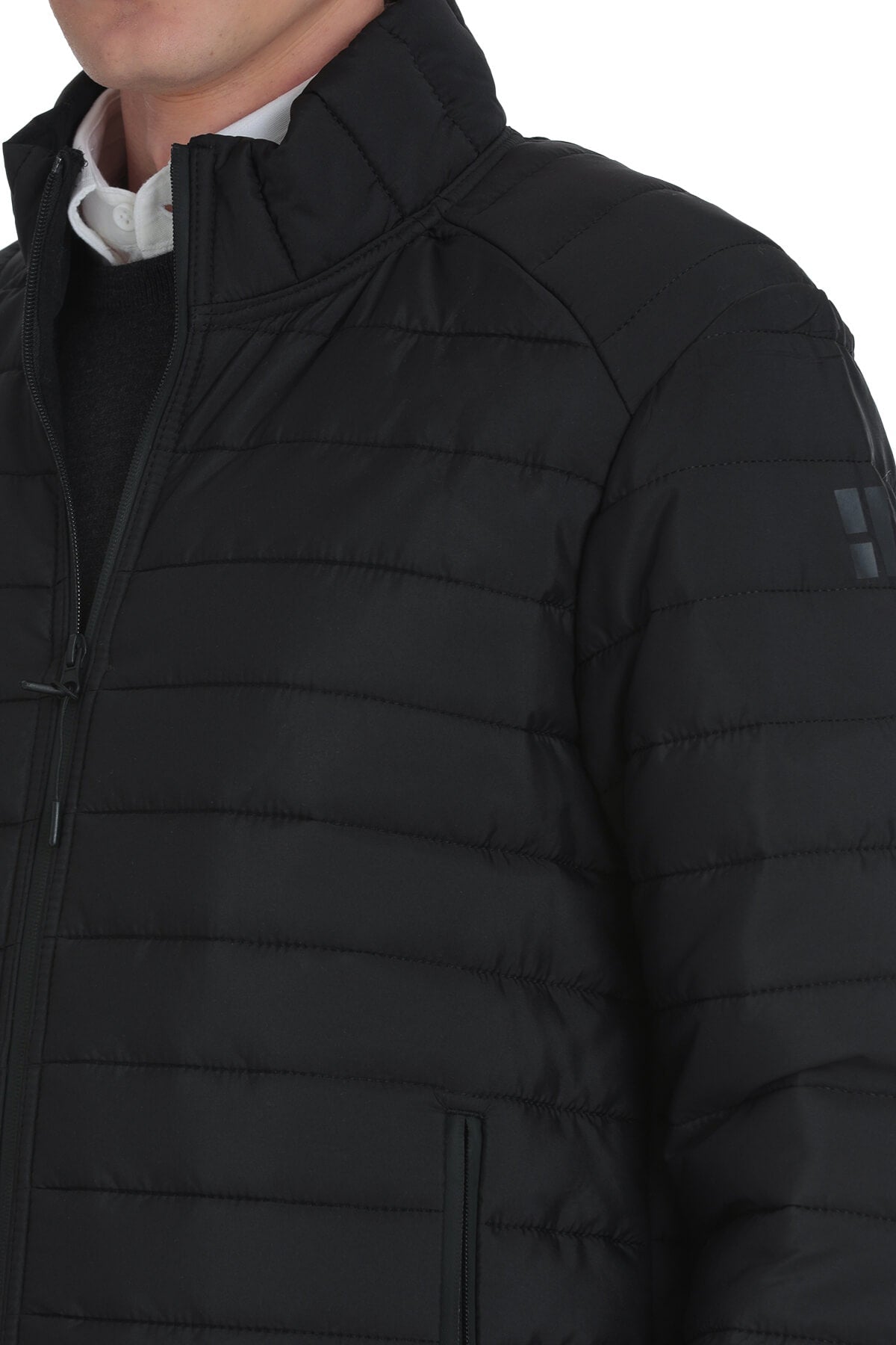 Black quilted puffer jacket with a high collar and subtle logo patch on the sleeve.