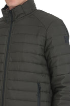 Dark olive green quilted puffer jacket with black zipper accents and a subtle brand logo patch on the sleeve.