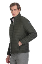 Dark olive green quilted puffer jacket with a high collar and zippered pockets.