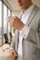 A sleek silver toned natural stone square cufflink on a man’s crisp white shirt sleeve
