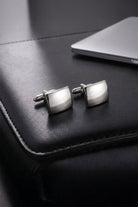 A pair of silver toned natural stone square cufflinks with a polished metallic finish and curved edges