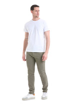 A man wearing a plain white short-sleeved t-shirt and olive green slim-fit trousers.