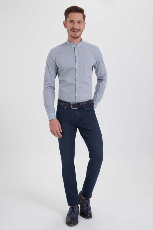 A man wearing a light blue button-down shirt with subtle white dot pattern and dark navy slim-fit jeans.