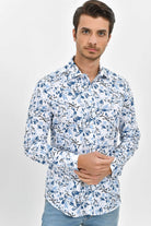 A man wearing a white long-sleeved button-up shirt with a blue and black floral pattern.