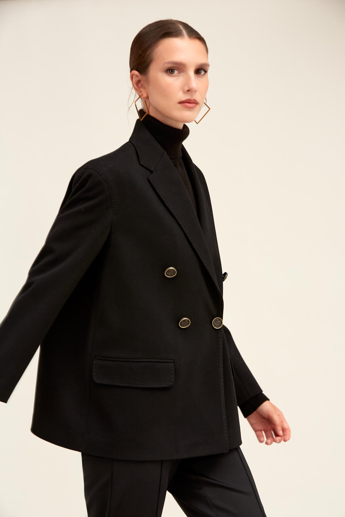 Black double-breasted blazer with gold-toned buttons and structured shoulders.