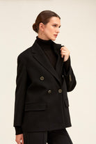 Black double-breasted blazer with metallic buttons and structured shoulders.
