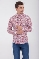 A man wearing a long-sleeved, button-up shirt with a delicate floral pattern in shades of pink and burgundy.