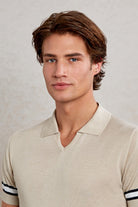 Beige textured knit polo shirt with black and white striped cuffs.