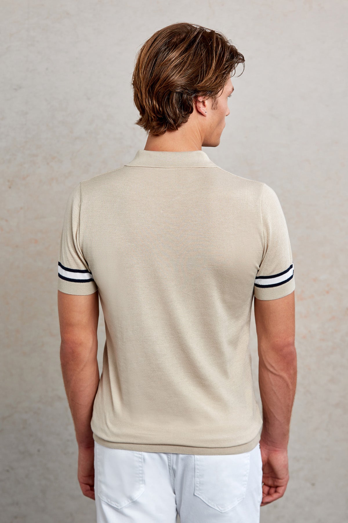 Beige short-sleeved polo shirt with black and white striped cuffs.