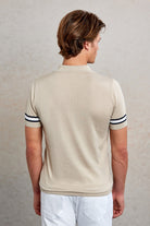 Beige short-sleeved polo shirt with black and white striped cuffs.