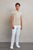 Beige polo shirt with black and white striped cuffs.