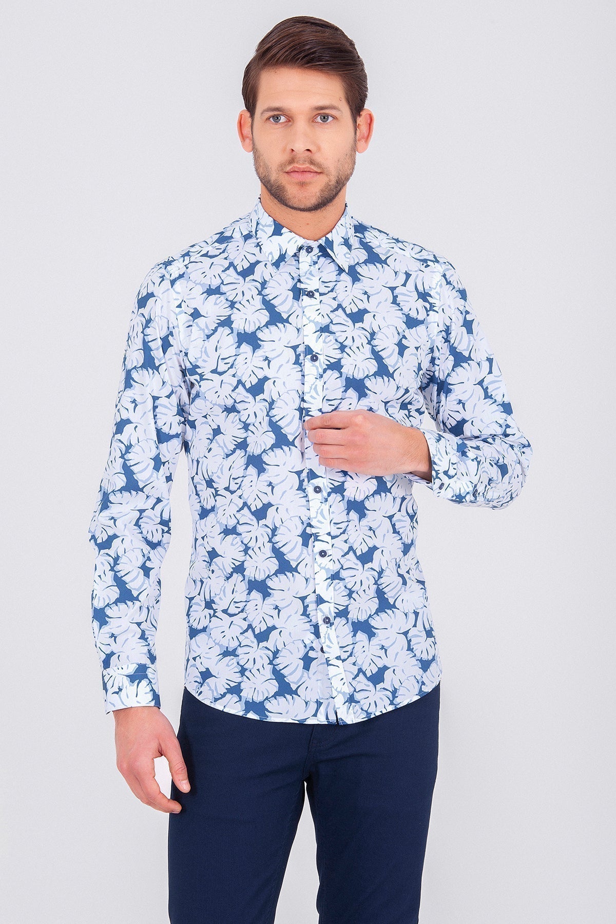 A men’s long-sleeved button-up shirt featuring a vibrant blue and white tropical leaf pattern.