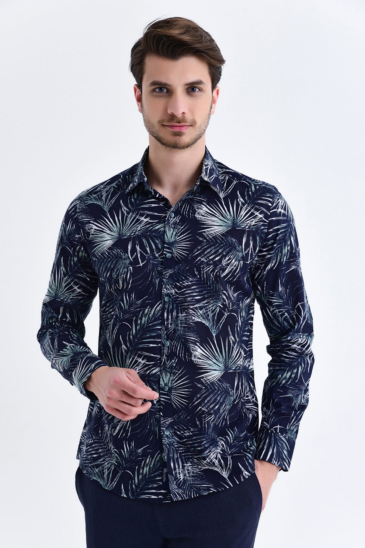 A navy blue long-sleeved button-up shirt featuring a bold white tropical leaf pattern.