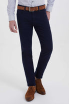 Navy blue slim-fit chinos with a brown leather belt and silver buckle