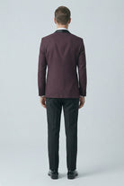 Slim fit classic tuxedo with a burgundy peak lapel jacket featuring black satin collar and matching cuffs worn with dark trousers