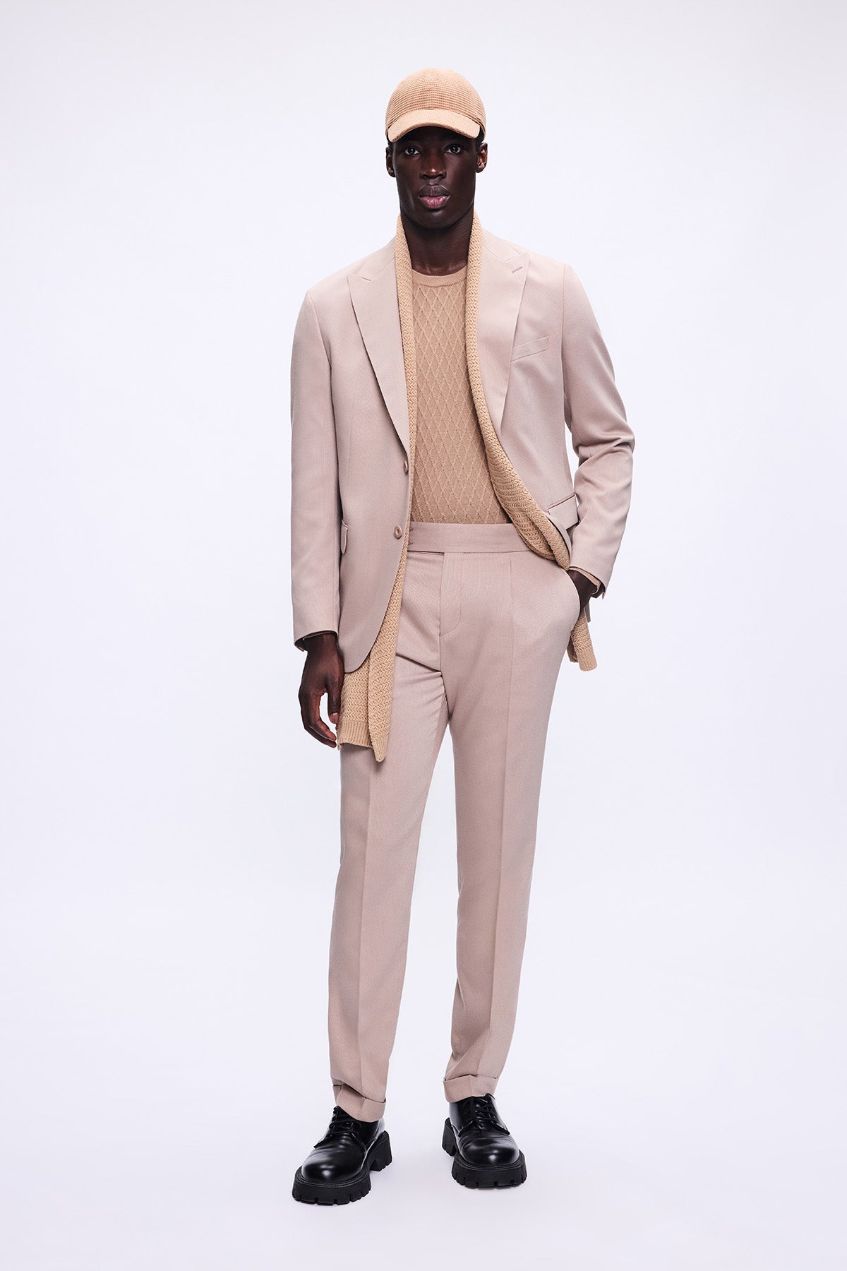 Beige tailored suit with matching trousers and a textured knit sweater underneath.