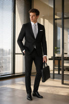 Black leather briefcase with structured design and top handle complementing a slim fit black classic suit