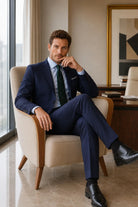 Man wearing a slim fit navy classic suit with notch lapel, light blue shirt, and dark green polka dot tie