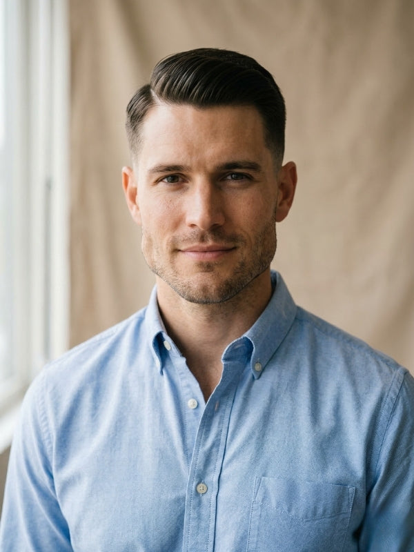 Man with a square face shape wearing a side part with medium fade and a light blue dress shirt