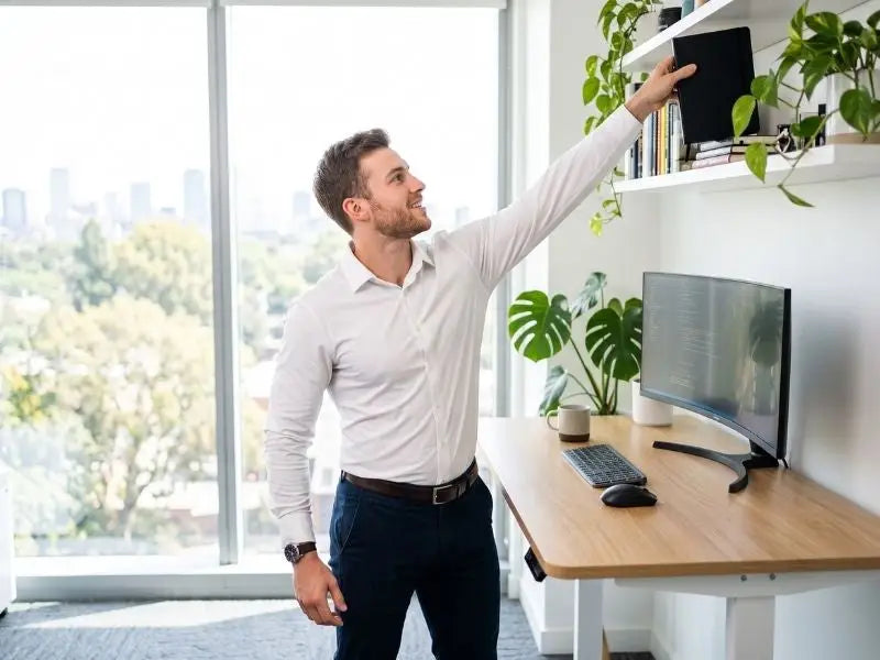 Man in a white stretch performance dress shirt reaching overhead at a standing desk without fabric pulling