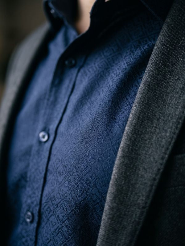 Close-up of a navy tonal jacquard pattern slim fit dress shirt under an open blazer