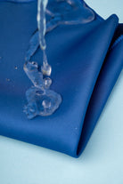 Deep blue satin fabric with water beading off its surface.