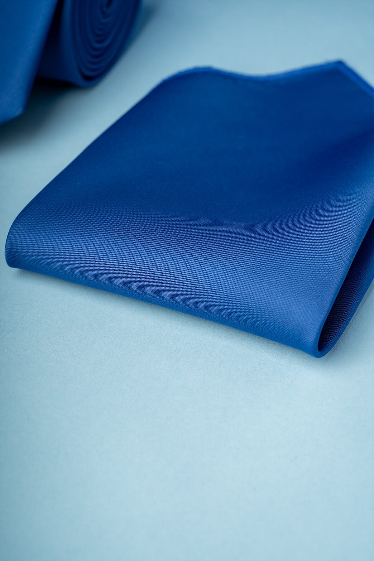 A rich royal blue silk pocket square, neatly folded and displaying a subtle sheen.