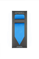 A vibrant blue tie, neatly packaged in a sleek black box with the brand name ’hatemoglu’ printed at the top.