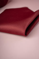 A rich burgundy silk pocket square, neatly folded with a smooth, lustrous texture.
