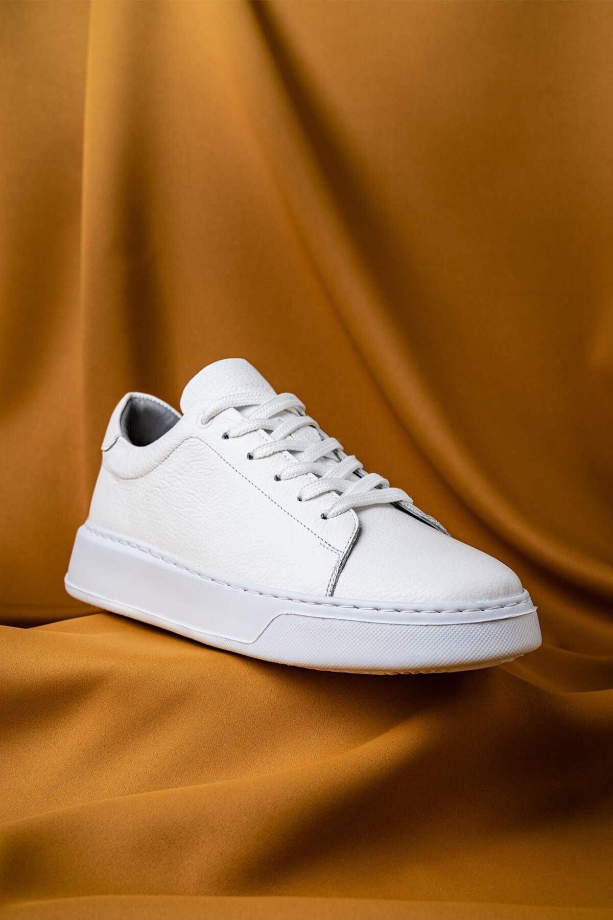 White leather low-top sneaker with clean stitching and a minimalist design.