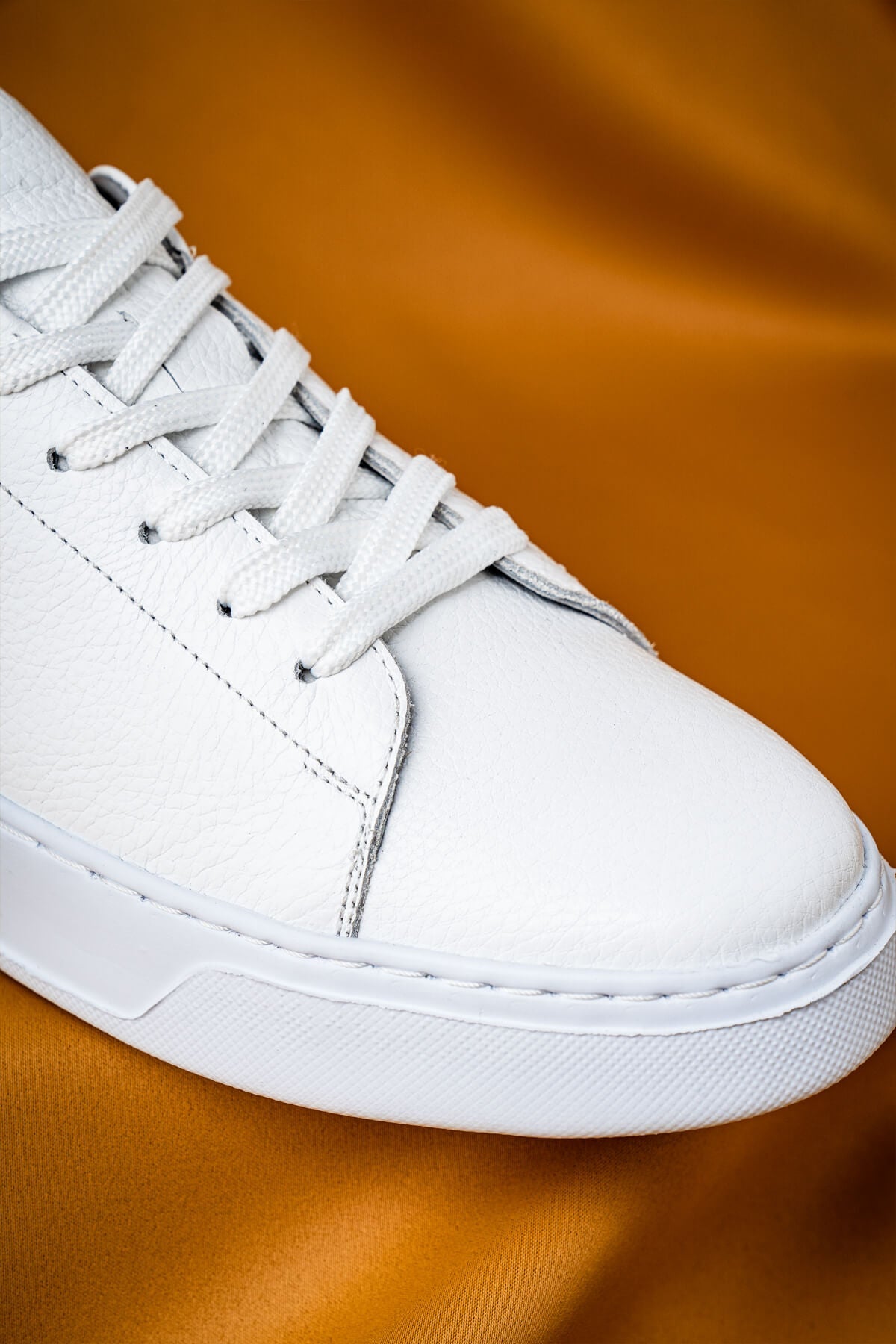 White leather low-top sneaker with matching laces and a clean, minimalist design.